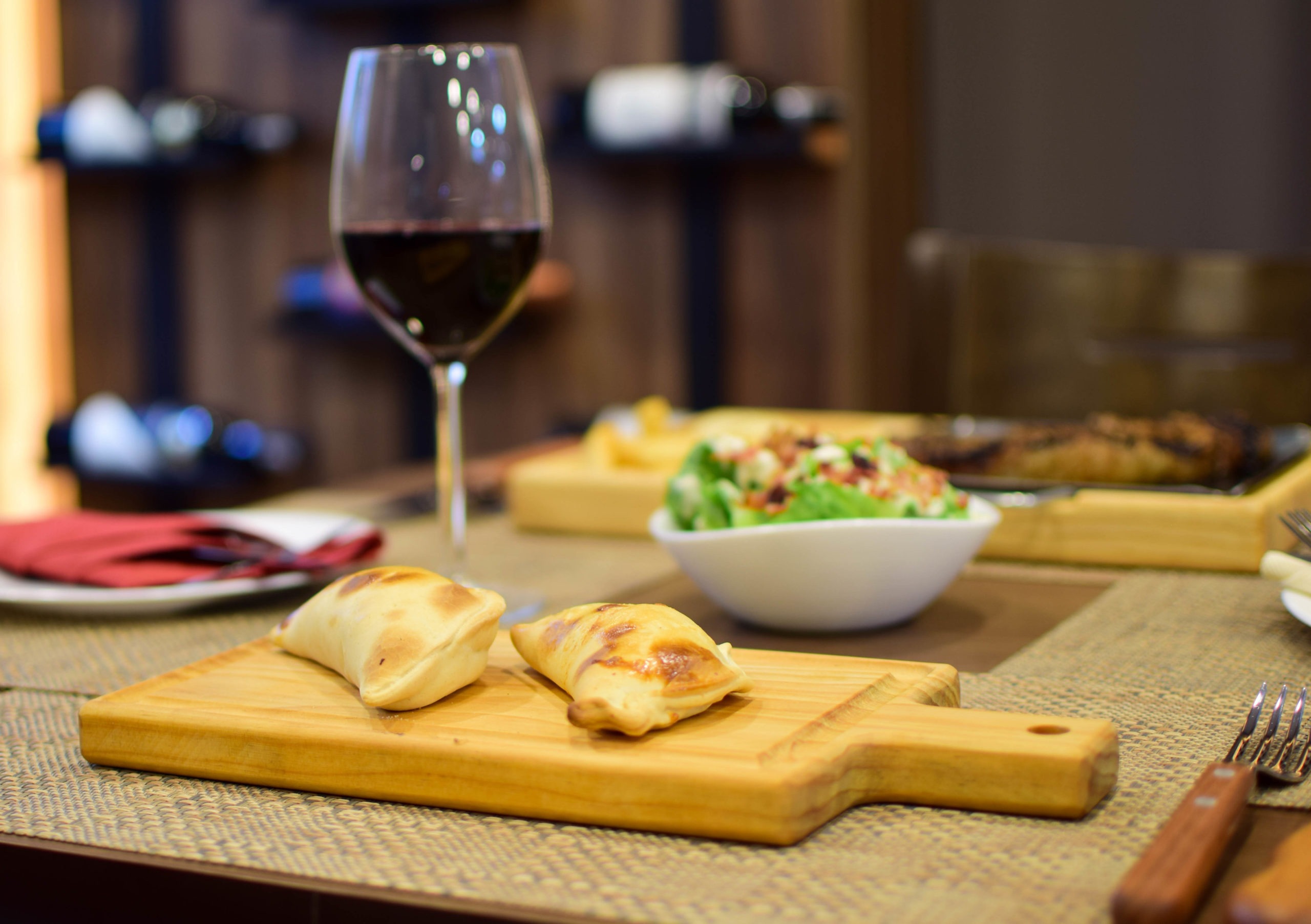 argentine-empanadas-with-glass-of-wine-wood-and-salad